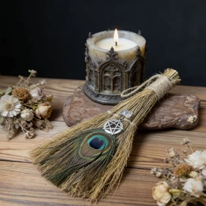 Detail of a handmade Wiccan besom with a peacock feather, pentagram charm and crystal