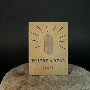 Macro-opname van een melkwitte kristalpunt op kraftkaart met de tekst You Are A Real Gem
