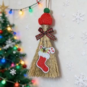 Christmas broom ornament with red knit hat and festive bow decoration on a lit tree