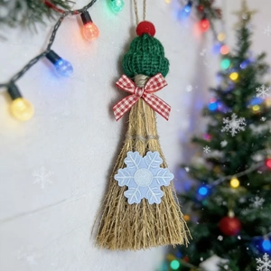 Detail of a handmade Christmas broom with a green knitted hat and snowflake embroidery