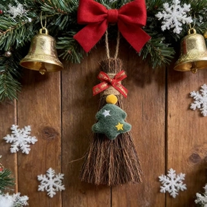 Detail of Christmas broom ornament with felt tree and red bow on wooden background