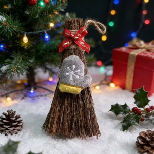 Close-up of a Christmas broom with 'Merry Christmas' ribbon and plush snowflake glove
