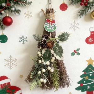 Close-up of decorative Christmas broom with pine cones, white berries, and a red ribbon bow