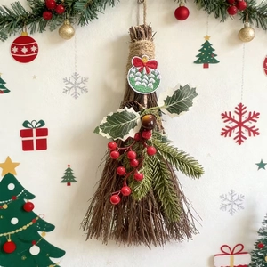 Close-up of decorative Christmas broom with red berries, pine needles and a ribbon bow