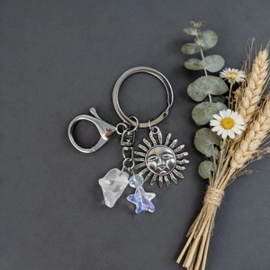 Natural crystal keychain with sun pendant and star bead on dark textured background