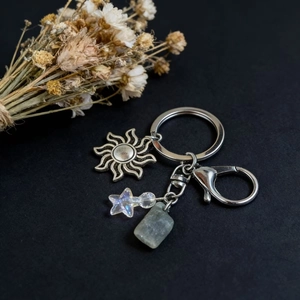 Natural crystal keychain with silver sun pendant and iridescent star bead on black background