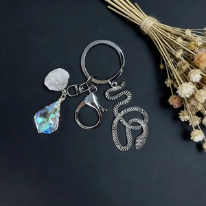 Natural crystal keychain with snake pendant and iridescent stone on dark background