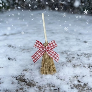 Miniature straw broom Christmas ornament with red plaid bow in a snowy winter scene