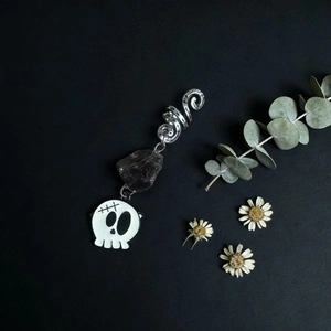 Detail of dark crystal dreadlock accessory with silver spiral and gothic skull charm
