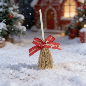 Close-up of mini wooden broom with red Merry Christmas ribbon on snowy background
