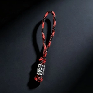 Detailed macro view of red and black braided paracord with a silver Viking knot bead