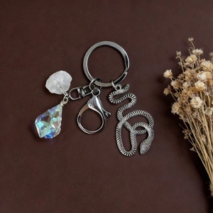 Detail of silver snake pendant and raw crystal charms on a rustic keychain