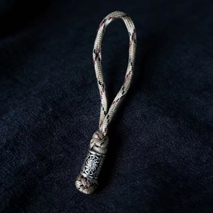 Detail view of a braided Viking keychain with a silver sun-patterned metal bead