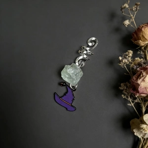 Detail of natural green crystal hair charm with purple wizard hat on dark background