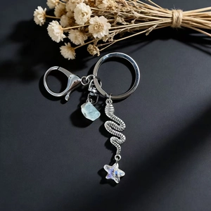 Detail of silver keychain with blue crystal stone, spiral metal and iridescent star pendant