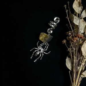 Macro shot of silver spider dreadlock jewelry featuring a raw citrine crystal stone
