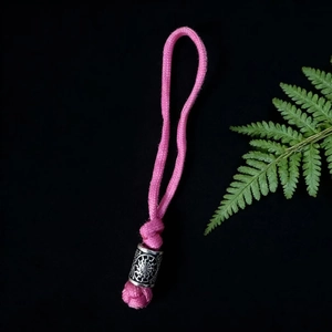 Detailed view of pink paracord keychain featuring an engraved silver sun pattern metal bead