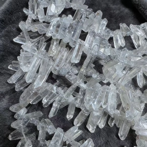 Natural clear quartz crystal point pendants on dark grey faux fur background