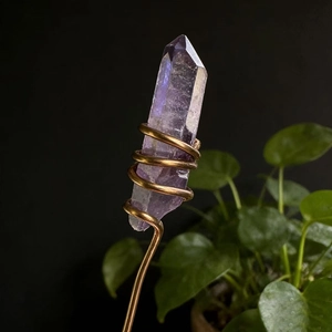 Detailed view of hand-wrapped natural amethyst crystal point with golden wire accents