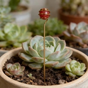 Detail view of handmade garden stake with red crystal ball and golden wire wrap in a succulent pot