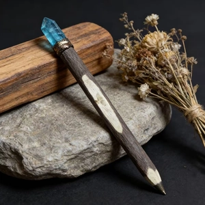 Close-up of wooden magic wand pen with blue raw crystal top on natural stone