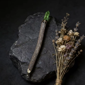Detailed close-up of a rustic wooden magic wand pen with a raw green crystal top