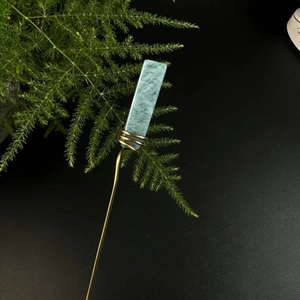 Macro detail of natural green crystal stone wrapped in copper wire on a golden hairpin
