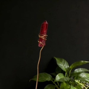 Macro detail of red crystal wand with gold wire wrapping against a dark background