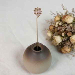 Detail of pink crystal ball hand-wrapped in gold wire on a ceramic base decor