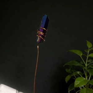 Macro detail of iridescent blue crystal hand-wrapped with copper wire on a decorative stem