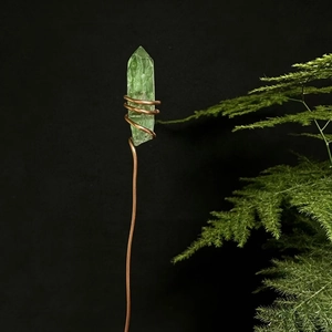 Macro view of green crystal flower stick wrapped in copper wire against black background
