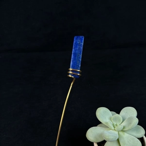 Detailed macro view of natural lapis lazuli crystal bound with gold copper wire on pin