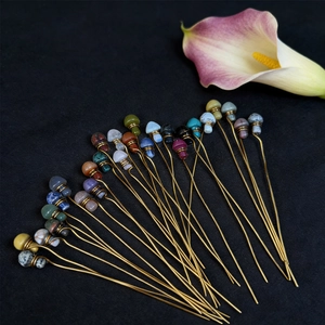 Handmade crystal mushroom hairpins with golden wire wrapping on a black background