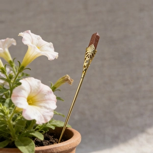 Macro detail of a gold hexagonal crystal flower stake placed in a terracotta pot