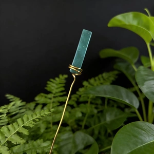 Detail of handmade gold wire wrapped green fluorite crystal on a sleek metal floral pick