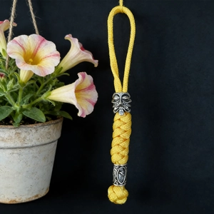 Detail of yellow paracord keychain featuring silver viking skull bead and intricate weaving