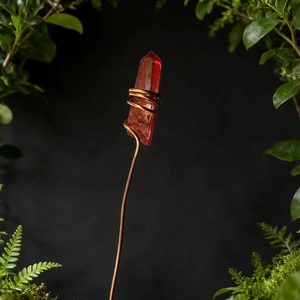 Detailed shot of handmade copper wire-wrapped red crystal hair pin with moss background