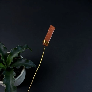 Detailed view of handmade natural red stone plant stake with elegant gold wire wrapping