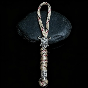 Macro detail of paracord keychain with viking helmet skull and silver runic beads