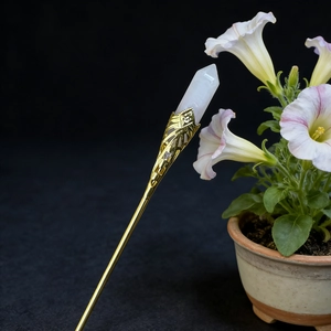Macro shot of gold filigree detail with hexagonal white crystal tip on hair pin