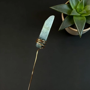 Detail of handcrafted gold wire wrapped around raw light green crystal flower arrangement