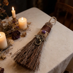 Detail of a decorative witch broom with purple stone and bronze dragon charm