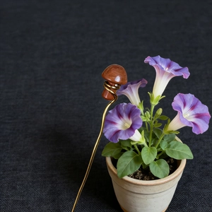 Detail of vintage copper hair pin with natural wooden mushroom and floral background