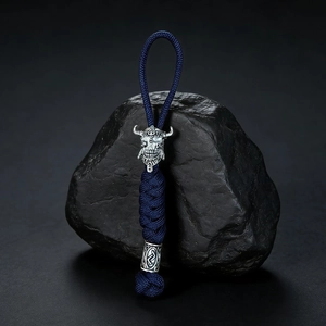 Macro detail of hand-woven blue paracord lanyard with silver Viking skull helmet charm