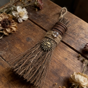 Detailed macro view of a rustic witch broom with hemp rope and sun pendant decoration