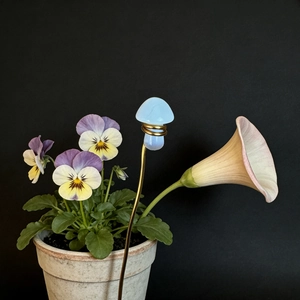 Artistic detail of a light blue matte crystal mushroom figurine on a golden metal stand