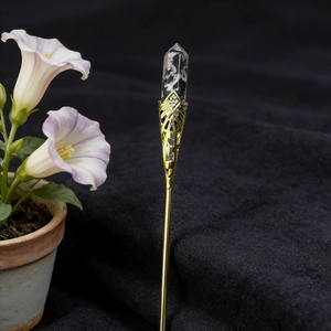 Detail of a handmade golden hair stick featuring a hexagonal crystal with marbled textures