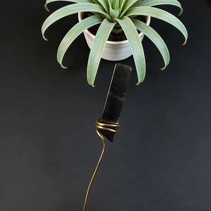 Detailed close-up of a black crystal stone wrapped in elegant golden wire handicraft