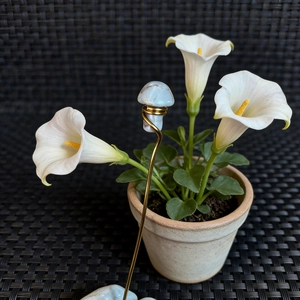 Macro detail of natural crystal mushroom garden stake with copper wire and calla lily