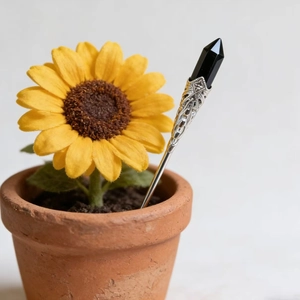 Close-up of a silver floral hair pin with a hexagonal black crystal stone in a pot